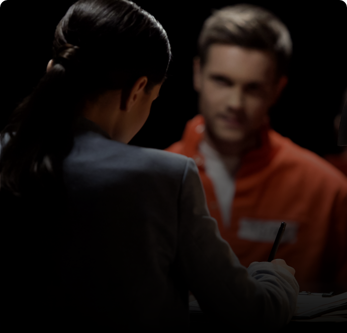 Lawyer speaking with a client in an orange prison jumpsuit.